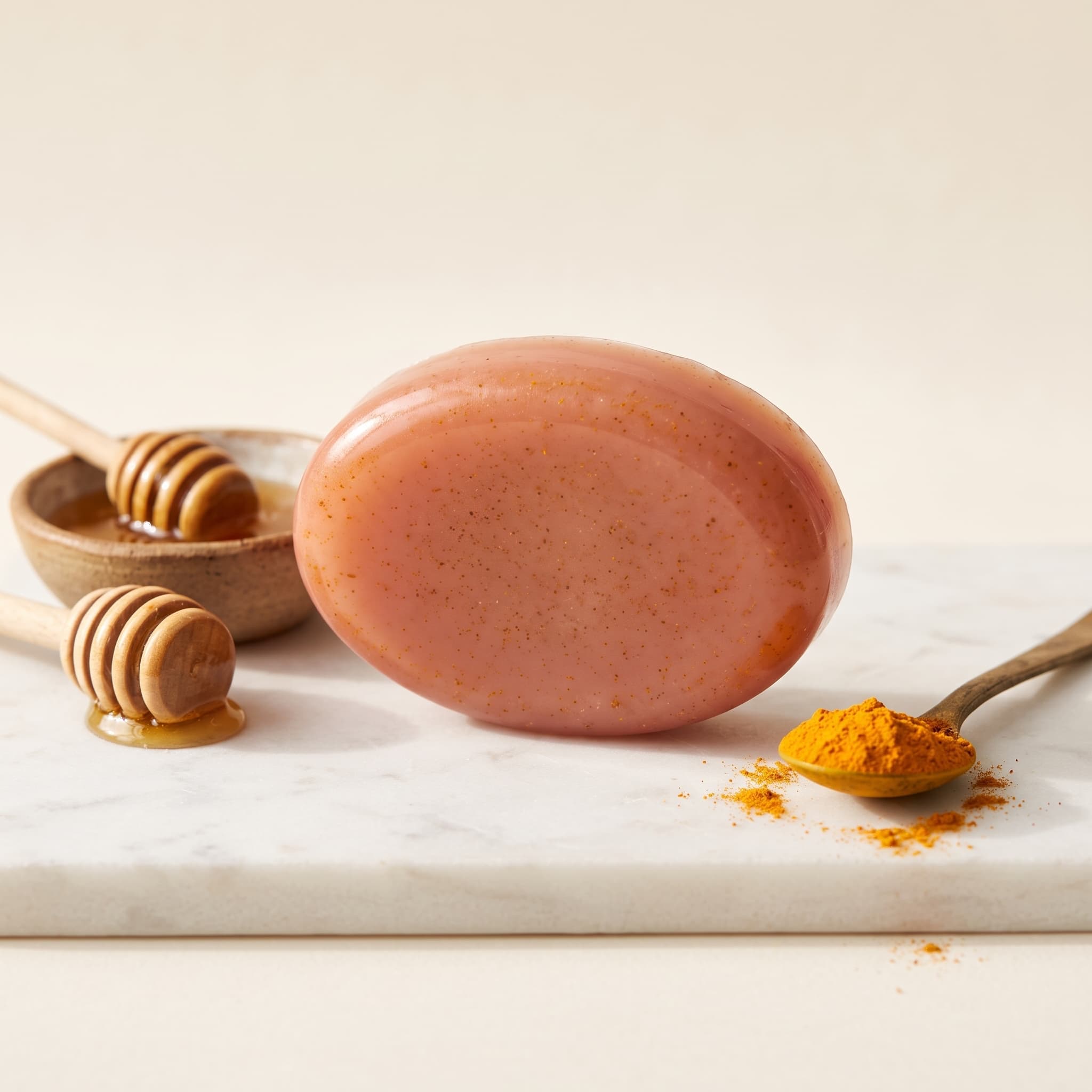 Jabón artesanal de cúrcuma y miel, pastilla ovalada color terracota rosado con motas de cúrcuma